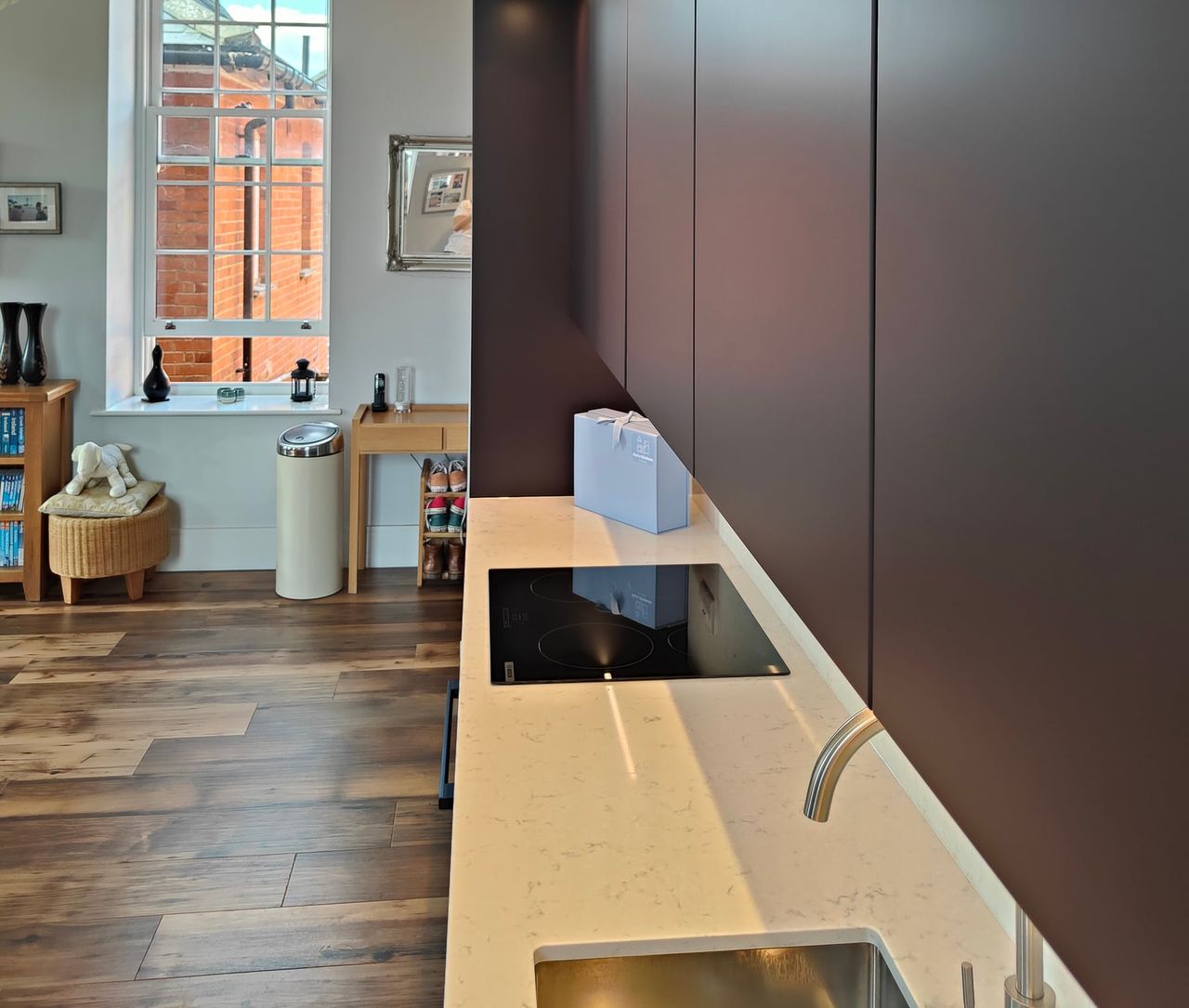 Dark cabinetry beside a pale worktop and sink.