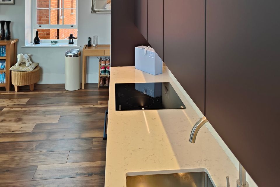 Dark cabinetry beside a pale worktop and sink.