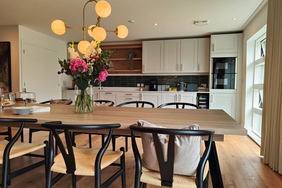 Furnished kitchen and dining room with flowers on the table.