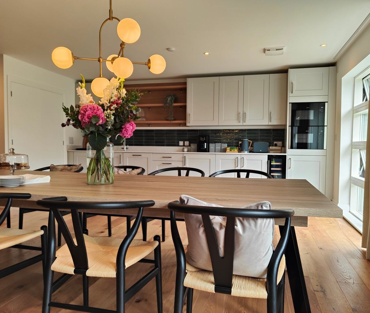 Furnished kitchen and dining room with flowers on the table.