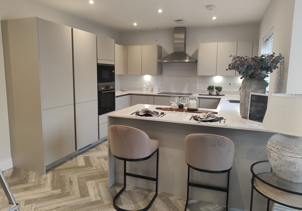 Pale kitchen cabinetry and a dressed island with upholstered stools.