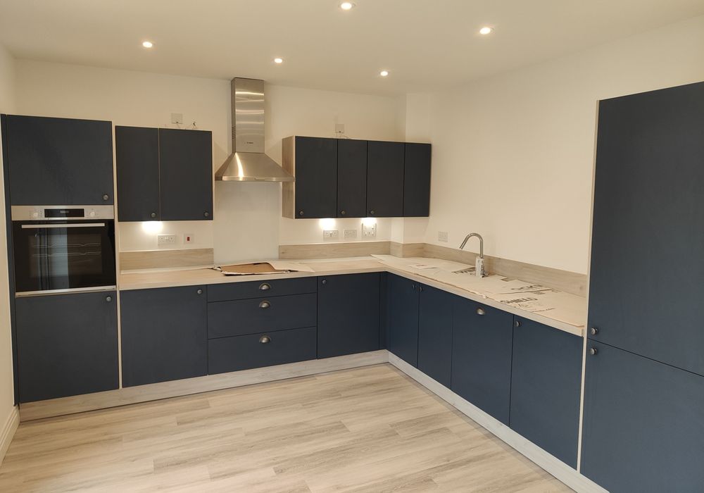 Navy kitchen cabinetry with pale worktops arranged around a corner.