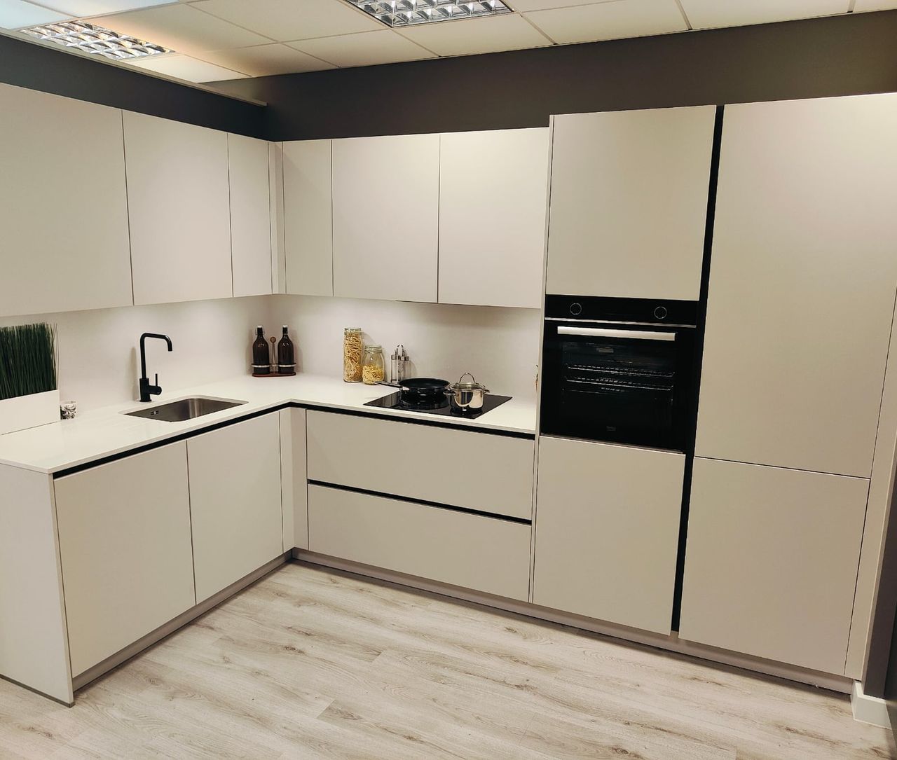 White fitted kitchen display with an integrated oven and worktop.