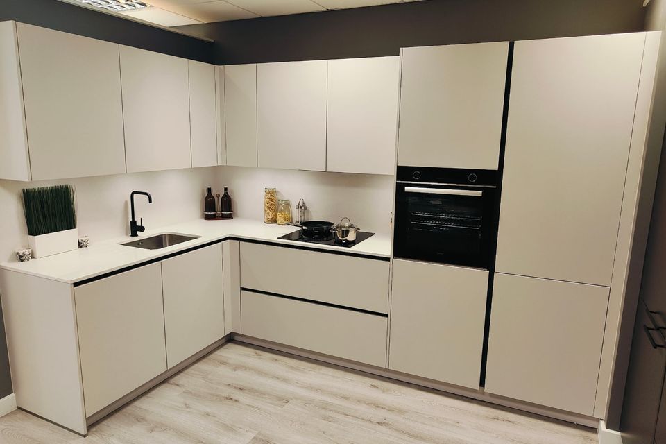 White fitted kitchen display with an integrated oven and worktop.